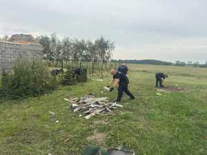 Policjanci sprzątają rozrzucone na posesji cegły, gałęzie, resztki dachów po przejściu nawałnicy.