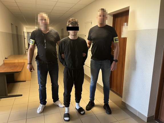 zatrzymany mężczyzna w kajdankach w towarzystwie dwóch policjantów