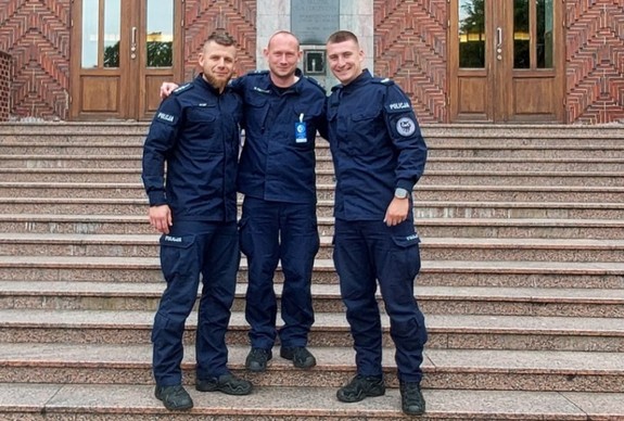 Trzej umundurowani policjanci pozują do zdjęcia.