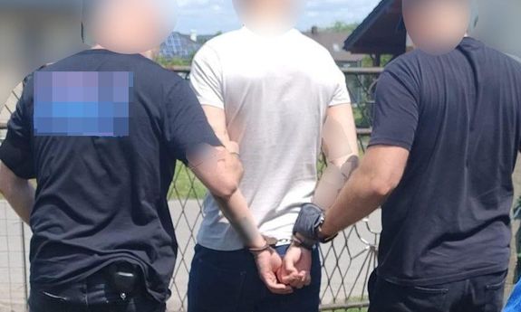 Dwaj nieumundurowani policjanci prowadzą zatrzymanego.