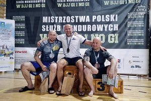 Zdjęcie przedstawia zawodników siedzących na podium.