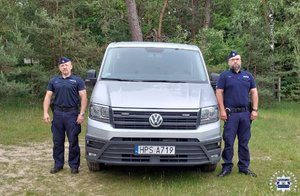 Dwaj policjanci przy policyjnym furgonie.