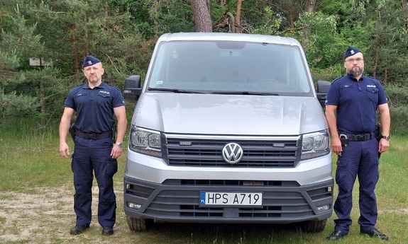 Dwaj policjanci przy policyjnym furgonie.