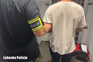 Policjant prowadzi zatrzymanego.