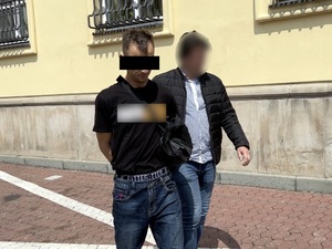 Nieumundurowany policjant prowadzi zatrzymanego.