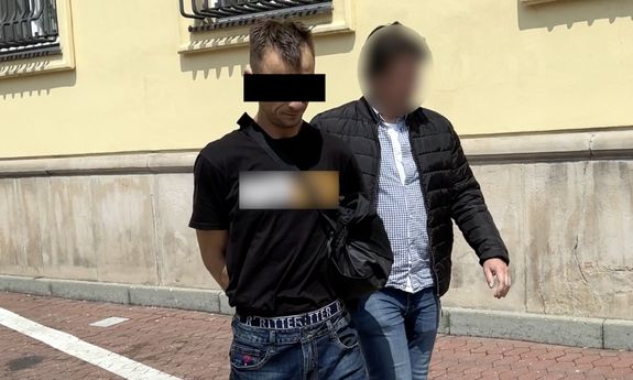 Nieumundurowany policjant prowadzi zatrzymanego.