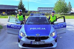 dwóch policjantów stoi koło radiowozu.