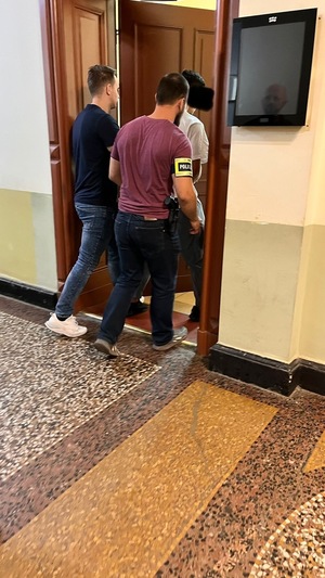 dwóch policjantów idzie z zatrzymanym.