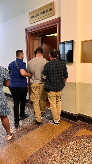 dwóch policjantów idzie z zatrzymanym.