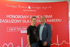 Odznaczony policjant w garniturze  z kobieta pozują do zdjęcia.