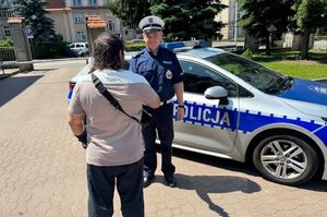 Mężczyzna dziękuje policjantom stojącym przy radiowozie.