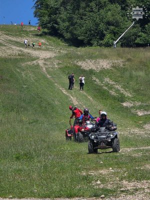 Policjant z kobietą na quadzie, za nim jedzie drugim quadem ratownik z drugim mężczyzną, którzy przewożą ranną.