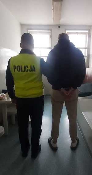 policjant stoi z zatrzymanym.