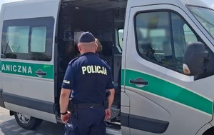 Funkcjonariusz Policji z zatrzymanym przy aucie Straży Granicznej.
