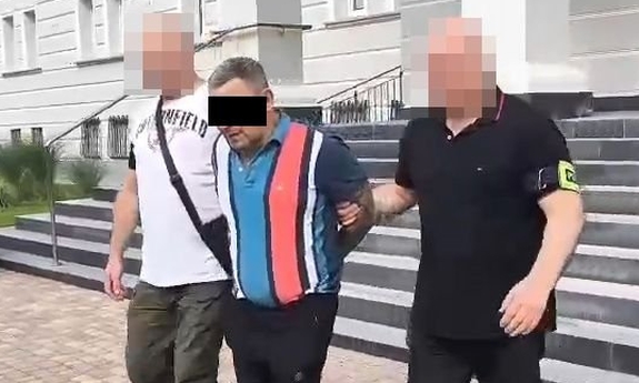 Dwaj funkcjonariusze prowadzą zatrzymanego.