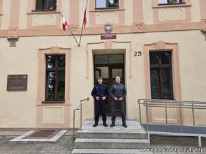 Dwaj funkcjonariusze przed budynkiem komendy Policji.