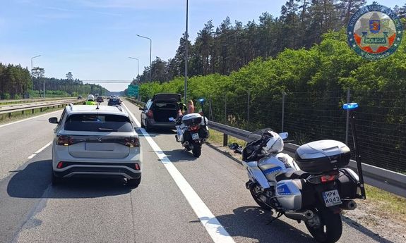 Stojące na poboczu drogi auto, za nim dwa policyjne motocykle, a obok na jezdni widać przejeżdżające pojazdy.