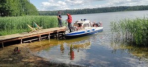Policyjna łódź dopływa do pomostu. Na pomoście stoi policjant.