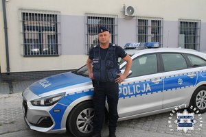 Umundurowany policjant przy radiowozie.