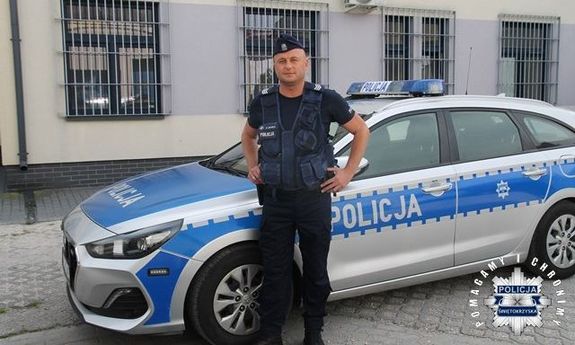 Umundurowany policjant przy radiowozie.