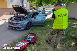 Policjant prowadzi oględziny samochodu.