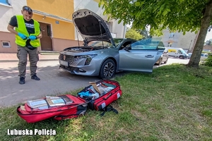 Policjant prowadzi oględziny samochodu.
