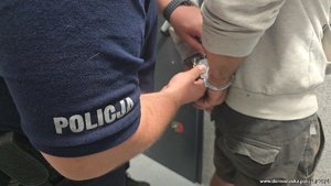 Policjant rozkuwa z kajdanek zatrzymanego.