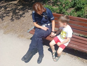 Policjantka siedzi z dzieckiem na ławce.
