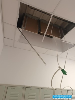 Uszkodzony sufit w sklepie. Z otworu powstałym po uszkodzeniu kasetonów wystają kable.