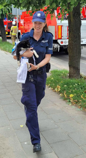 Policjantka niesie na rękach kota ewakuowanego z pożaru.