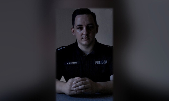 Policjant siedzi przy biurku.