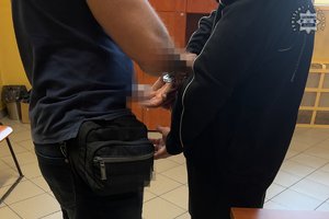 Policjant zakłada zatrzymanemu kajdanki.