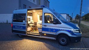 Pies siedzi we wnętrzu radiowozu typu bus.