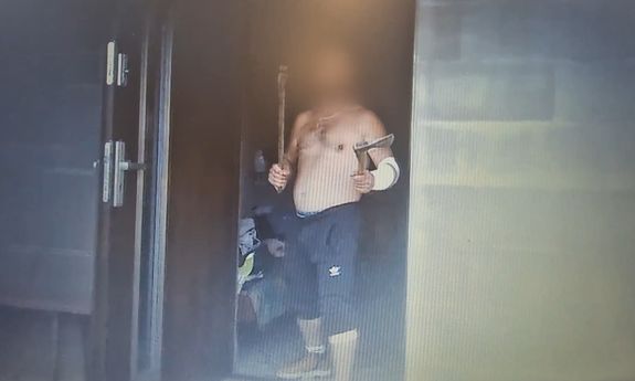 Półnagi mężczyzna trzyma w rękach dwie siekiery.