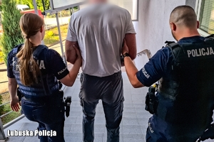 Dwoje umundurowanych policjantów prowadzi zatrzymanego.