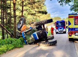 Ciągnik rolniczy leżący na boku na jezdni.