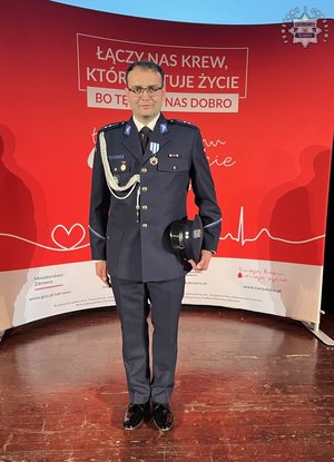 Umundurowany policjant pozuje do zdjęcia.