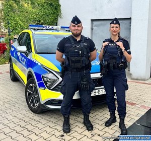 Dwoje policjantów z patrolu, za nimi radiowóz.