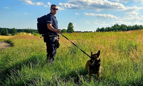 Policjant z psem na smyczy w trakcie poszukiwań.