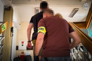Policjant z zatrzymanym, który idzie przed nim.