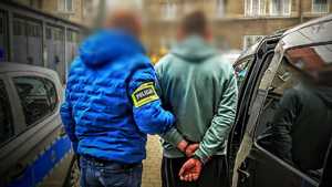policjant idzie z zatrzymanym.