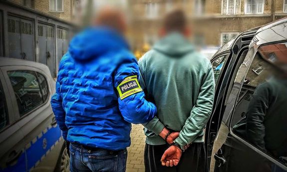 policjant idzie z zatrzymanym.