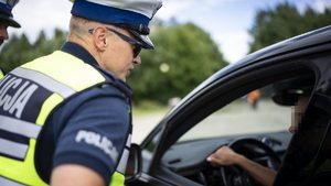Policjant ruchu drogowego rozmawia z kierowcą w aucie.