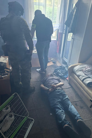 Policjanci w mieszkaniu, zatrzymany leży na podłodze.