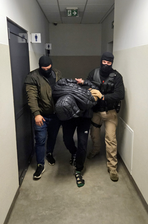 Dwaj policjanci prowadzą zatrzymanego.