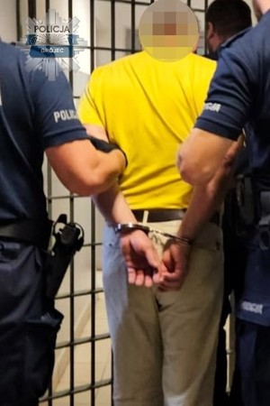 Dwaj policjanci prowadzą zatrzymanego.