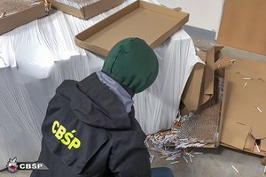 Policjant CBŚP przy zabezpieczonych papierosach.