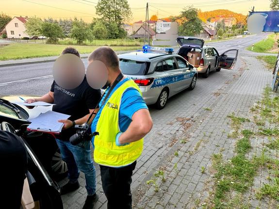 Dwaj policjanci przy zatrzymanym aucie.