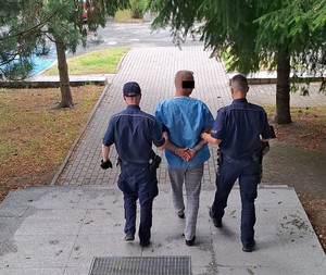 Dwaj policjanci prowadzą zatrzymanego.