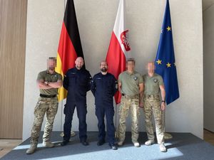 Trzej kontrterroryści i dwaj policjanci pozują do zdjęcia. W tle flagi Niemiec, Polski i Unii Europejskiej.
